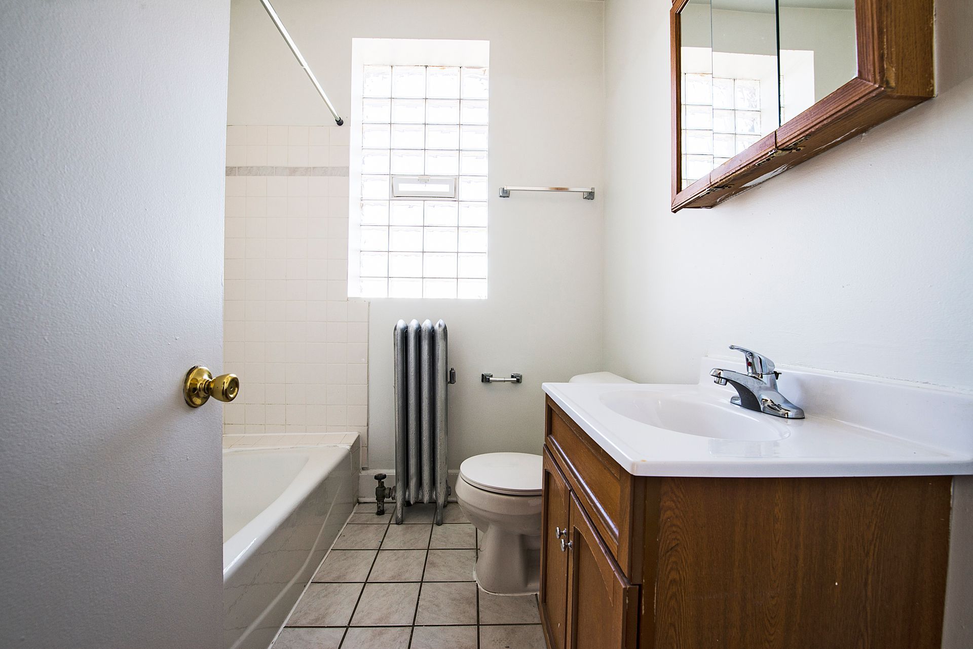 Empty room with hardwood floors, white walls, closet, open door, and radiator.