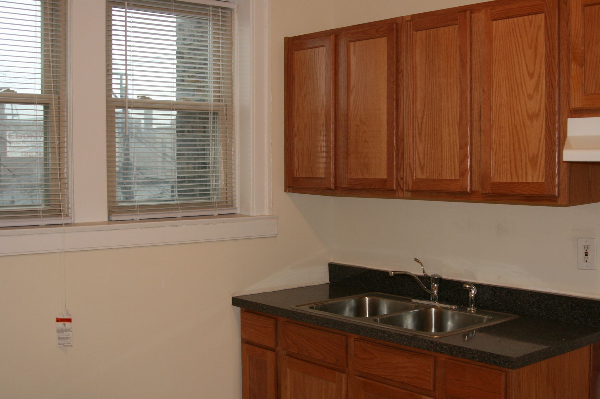 Kitchen with white appliances, brown cabinets, and white tiled floor. A window is in the center.