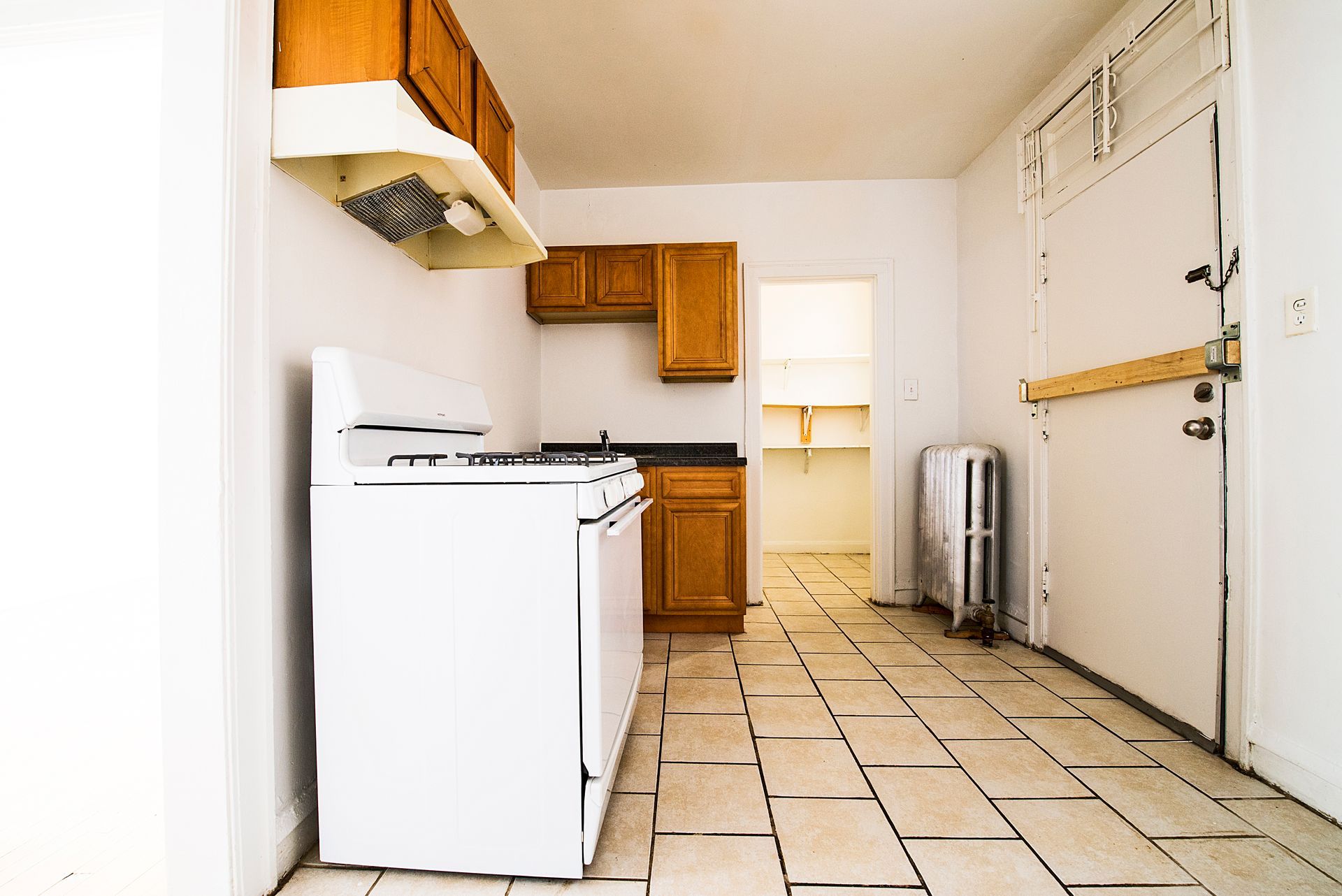 Small kitchen with white appliances, wooden cabinets, and tile floor.