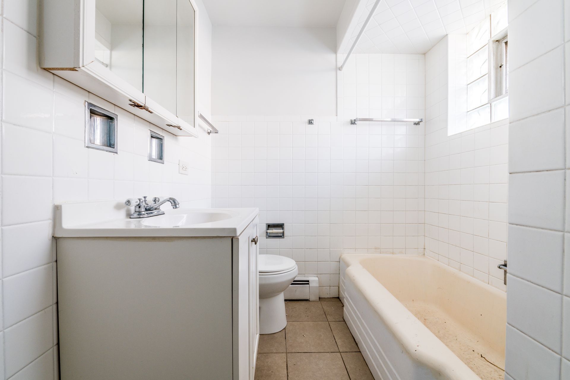White bathroom with a sink, toilet, tub, and mirrored medicine cabinet.