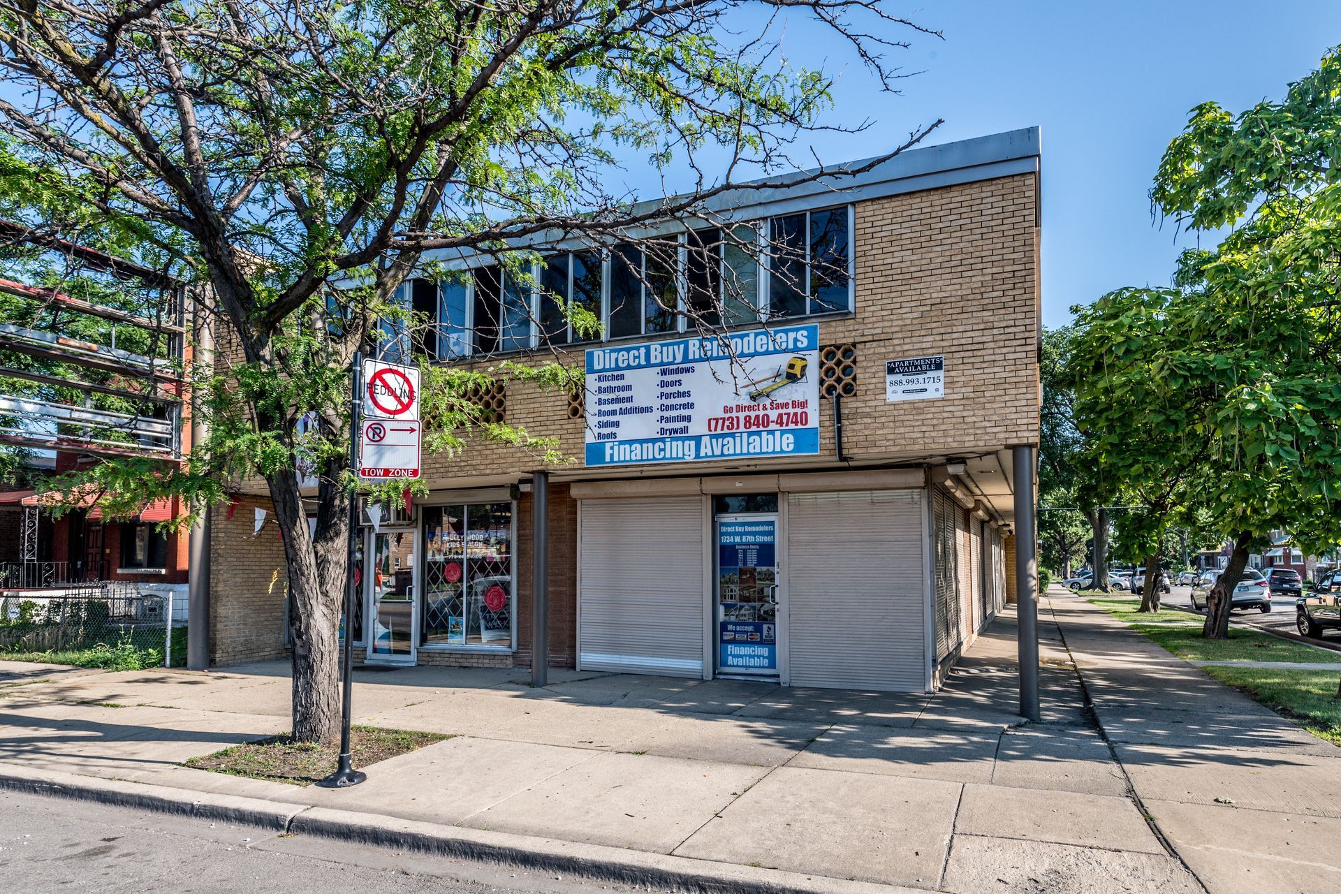 Two-story building with storefronts and a no-left-turn sign on a city sidewalk.