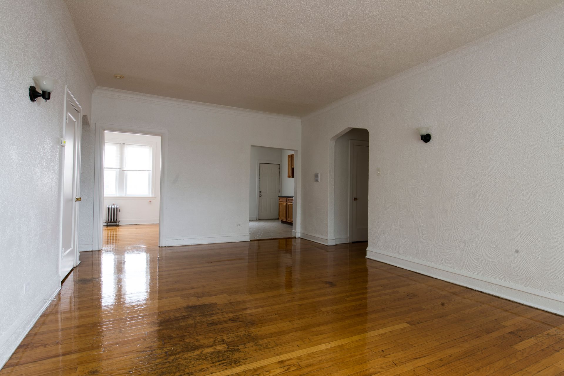 Empty apartment interior with wooden floor, white walls and three doorways.
