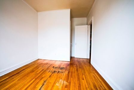 Empty room with hardwood floors, white walls, and a door.