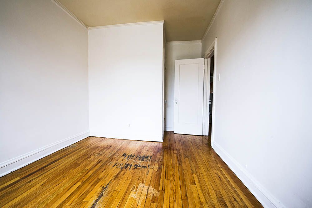 Empty room with hardwood floors, white walls, and a doorway.