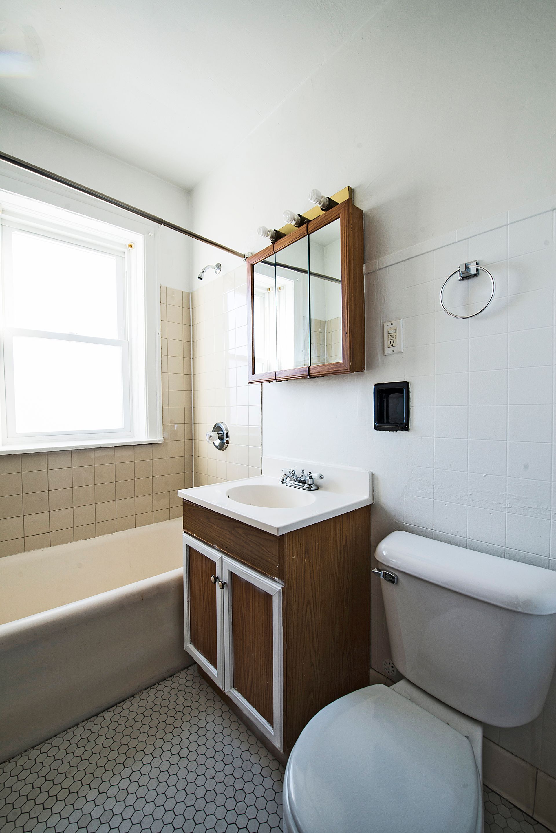 Bathroom with tub, toilet, vanity, and mirrored medicine cabinet; white and wood tones.