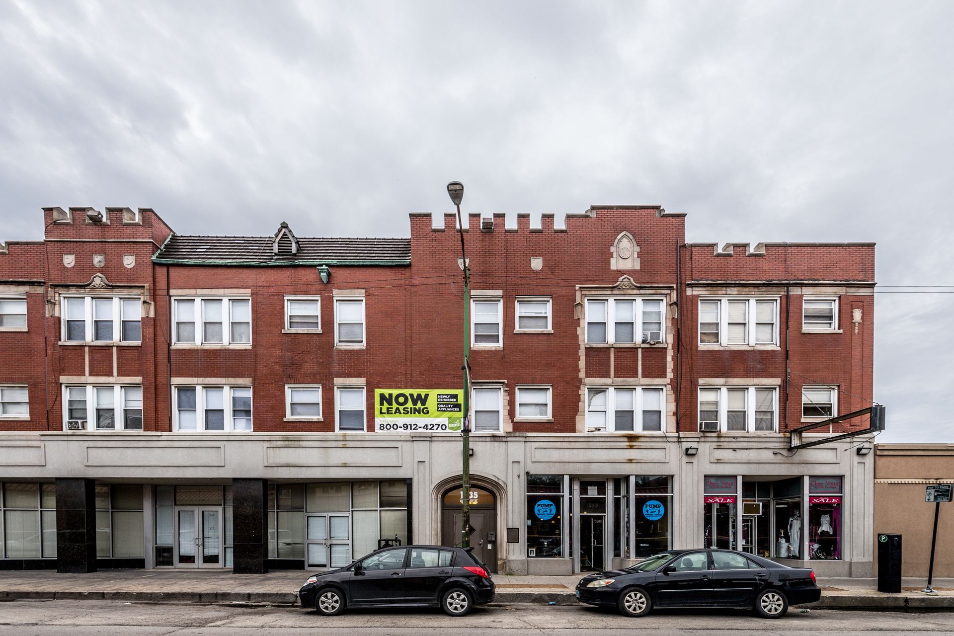 Building exterior with arched doorway and business windows on a city street.
