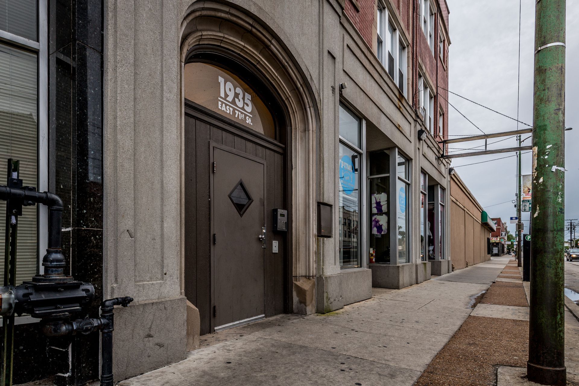 Gray building entrance with arched doorway and address 