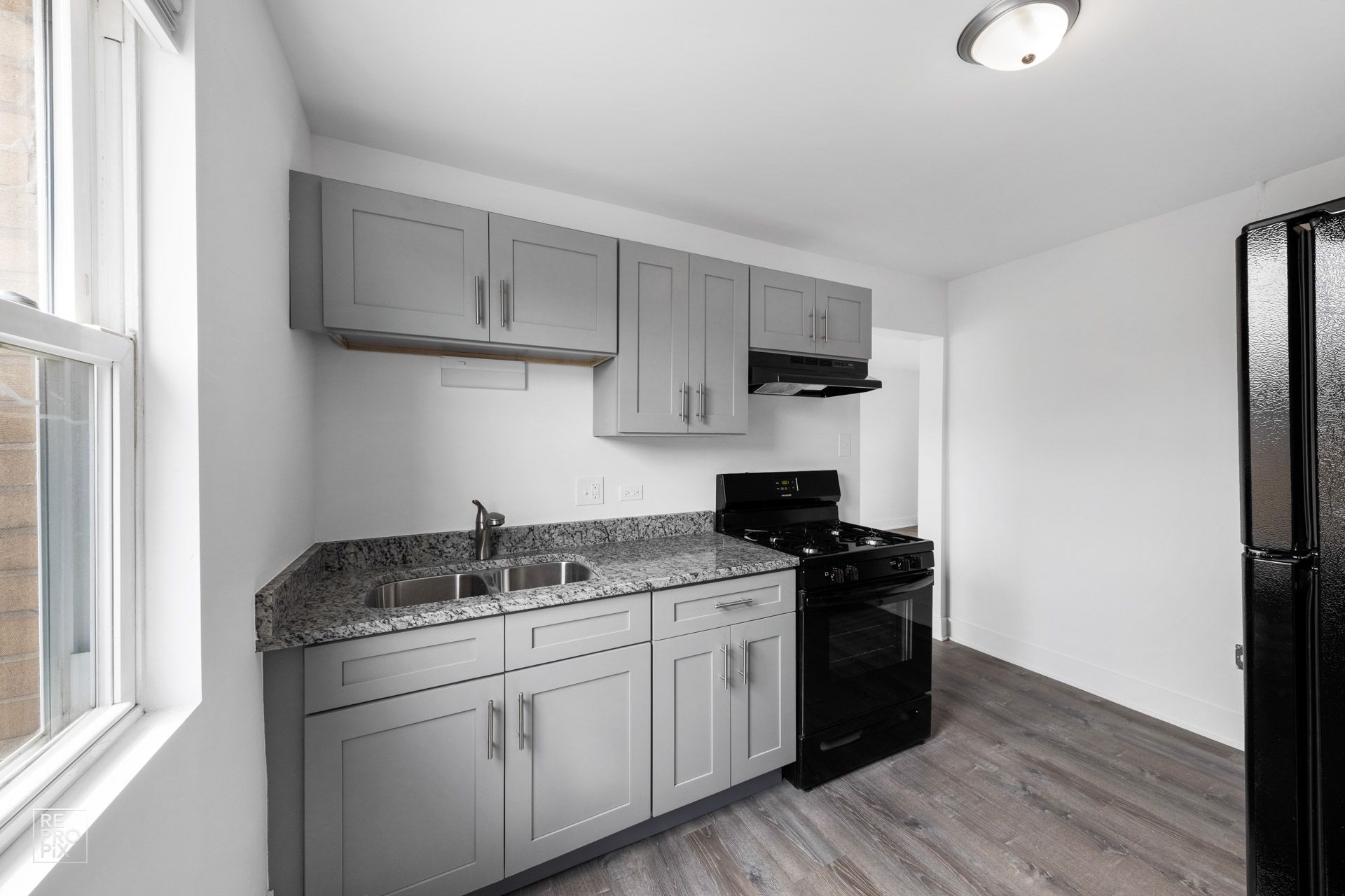 Gray kitchen cabinets, granite counters, black appliances.