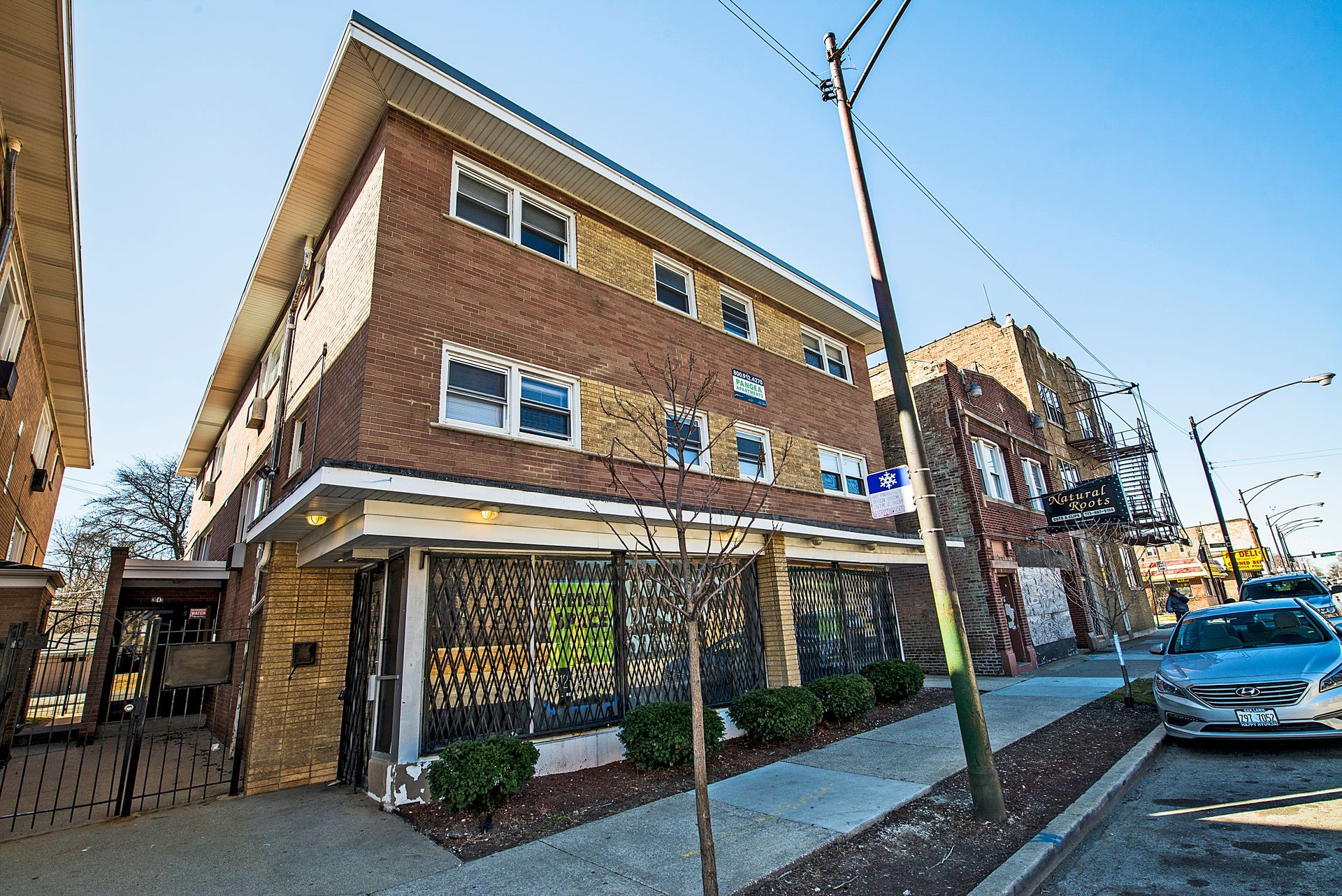 Brick apartment building with street view, two stories, shops below, clear sky, sunny day.