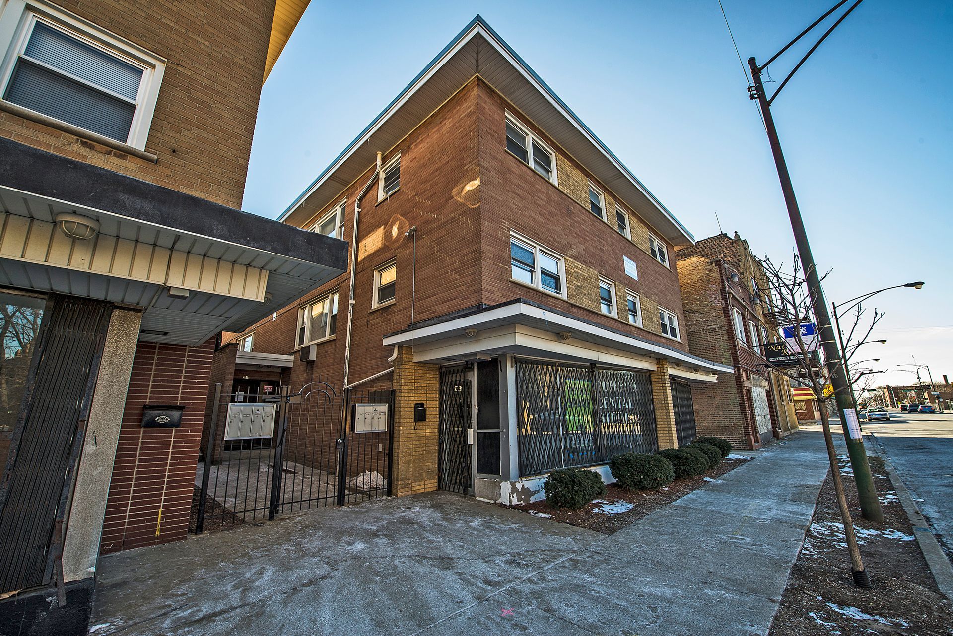 Brick apartment building on a city street, with sidewalk and streetlamp visible.