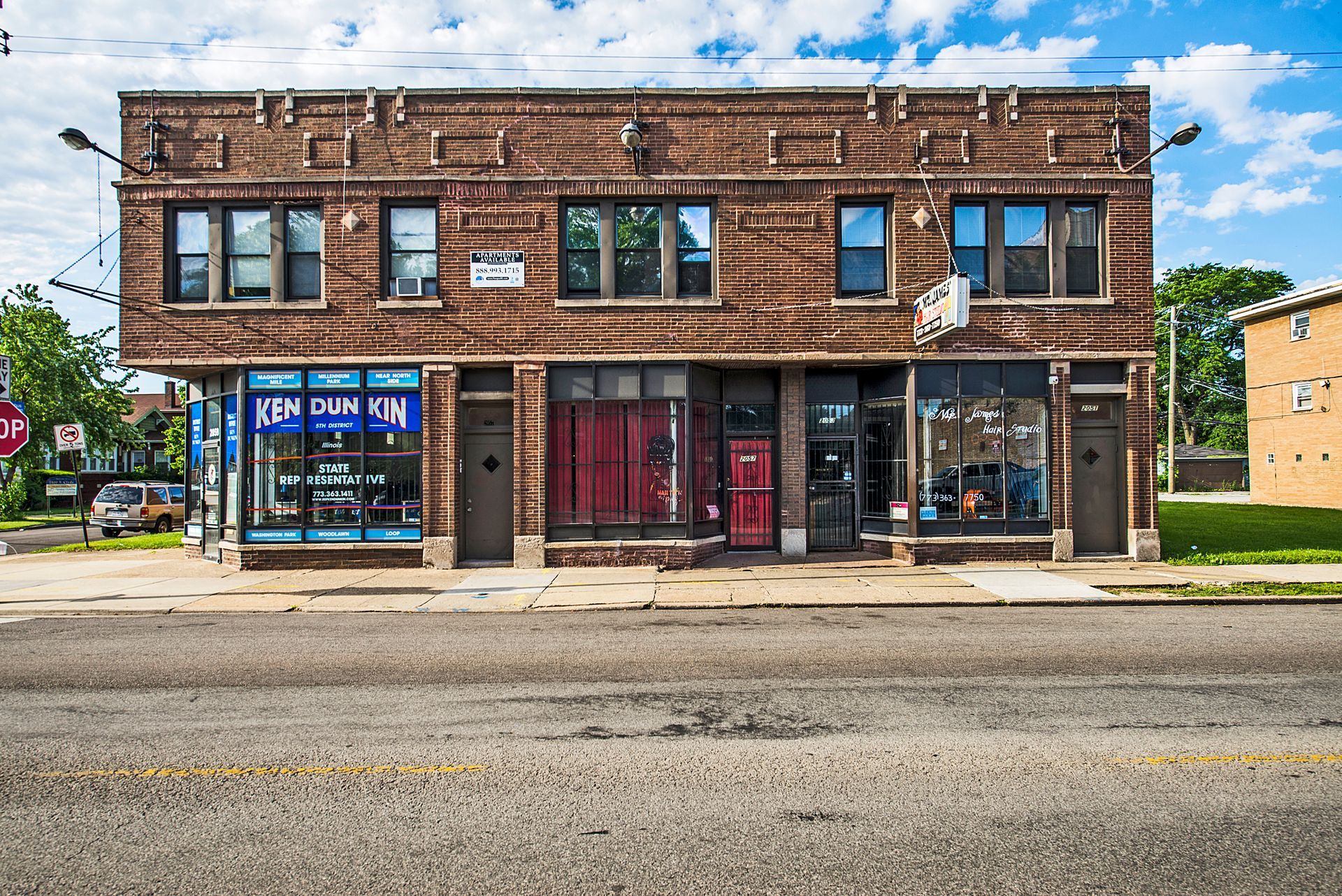 Two-story brick building with businesses on the ground floor, street in front, blue sky.