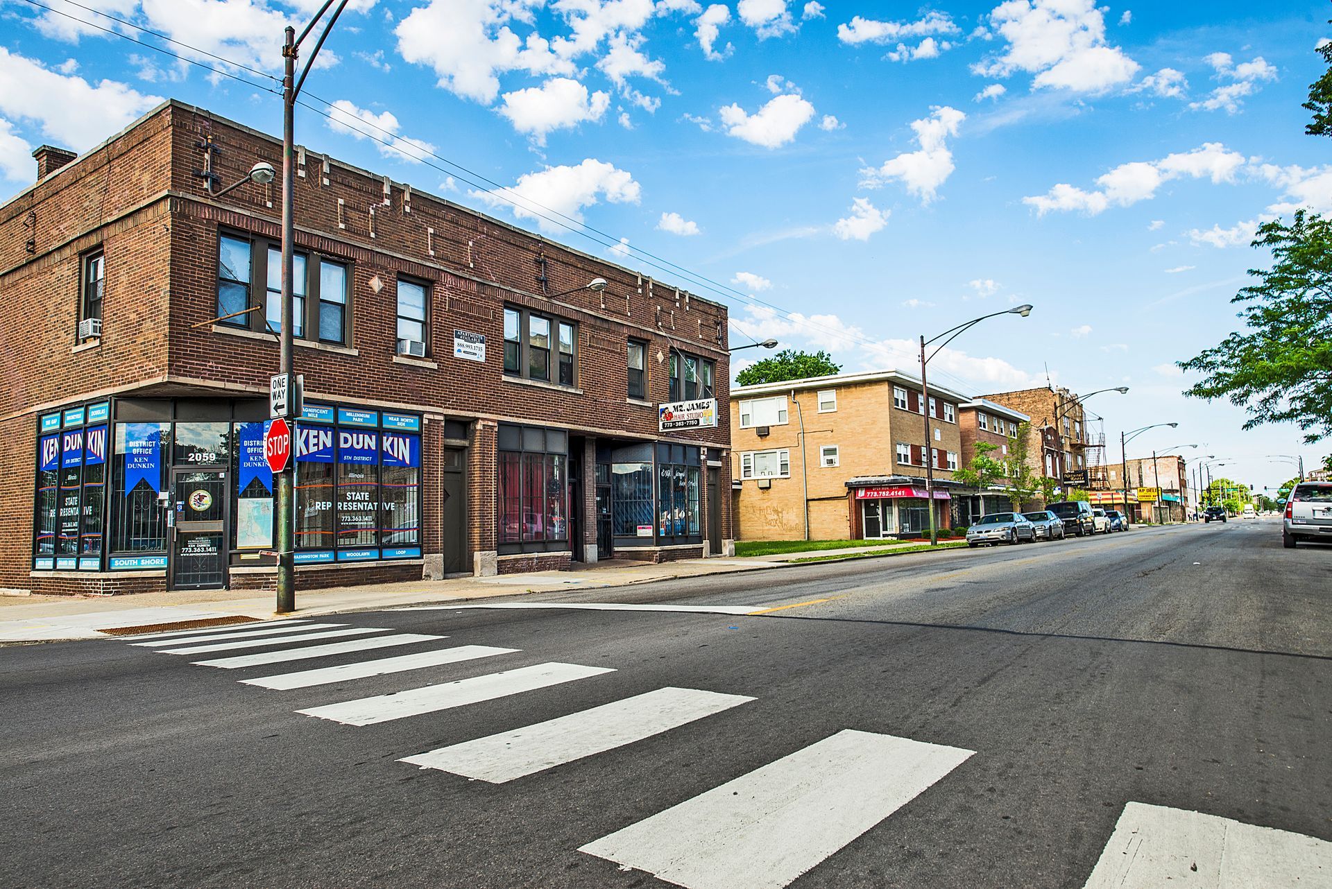 Street scene with crosswalk, brick buildings, and blue sky.