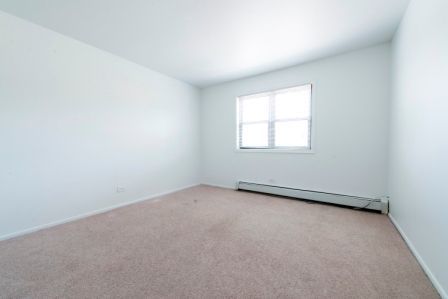 Empty room with beige carpet, white walls, and a window.