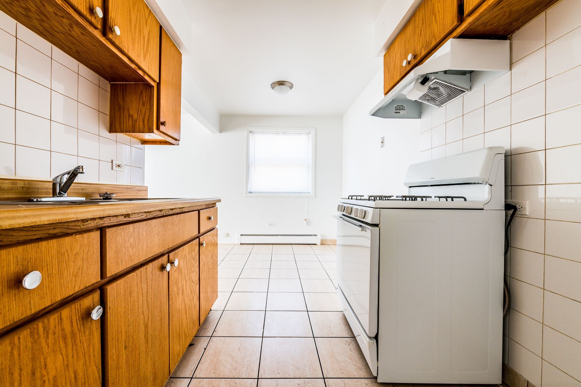 Kitchen with wood cabinets, white stove, and tile backsplash.