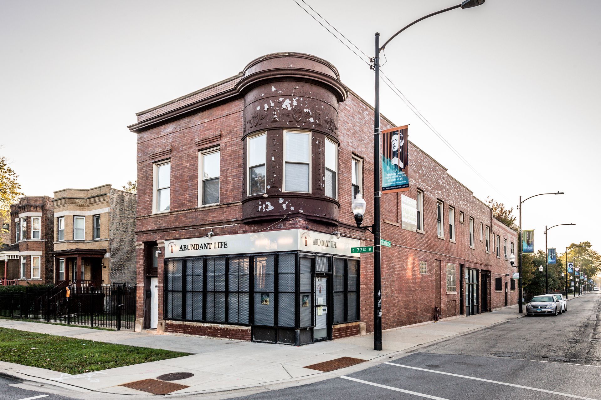 Brick building on a street corner with large windows, light post, and a car parked on the street.