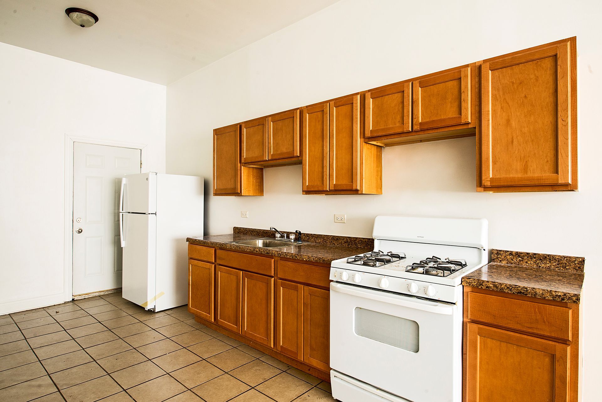 Kitchen with wooden cabinets, white appliances, and brown countertops.