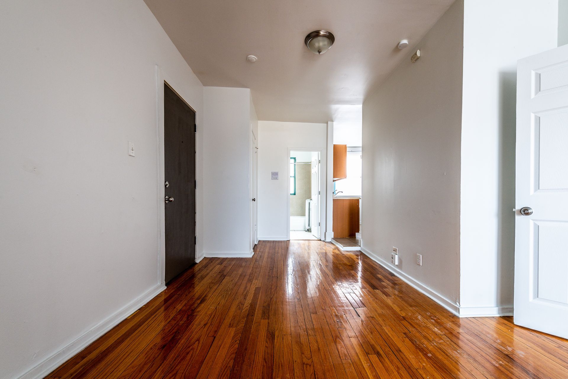 Empty apartment interior with hardwood floors and white walls.