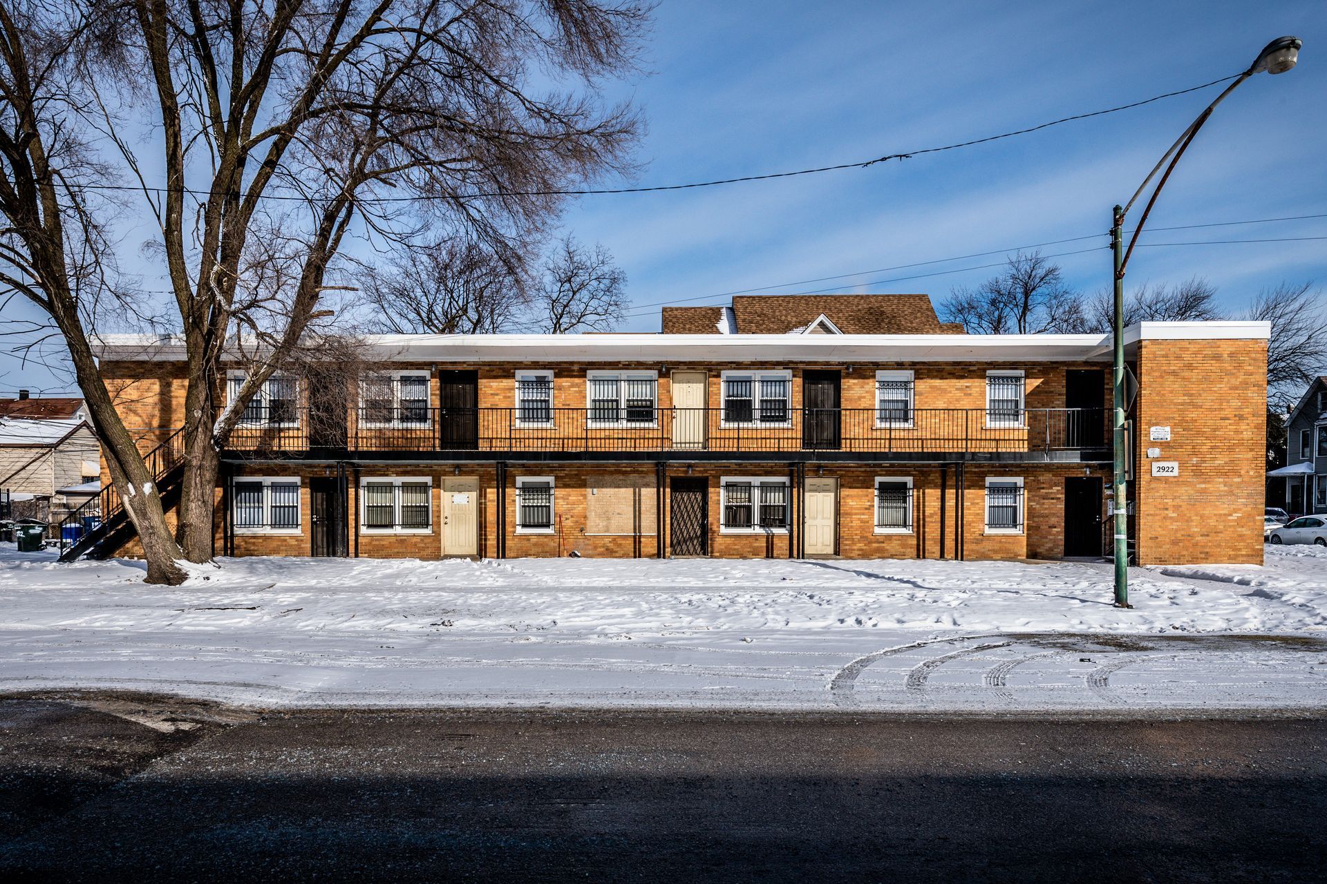 Two-story brick building in the snow, with boarded-up windows and a bare tree in the foreground.