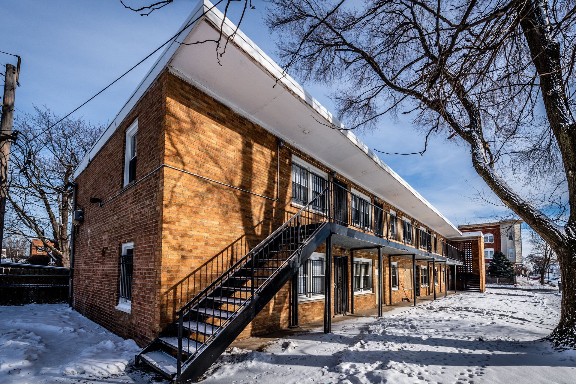 Two-story brick apartment building covered in snow, with exterior staircase.