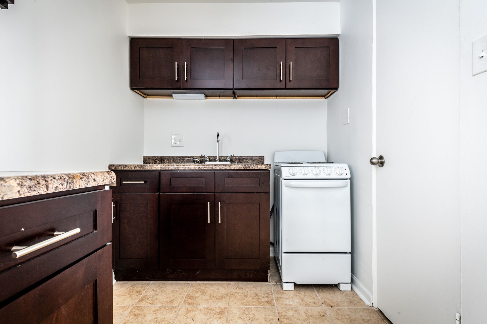 Small kitchen with dark brown cabinets, a white stove, and light countertops.