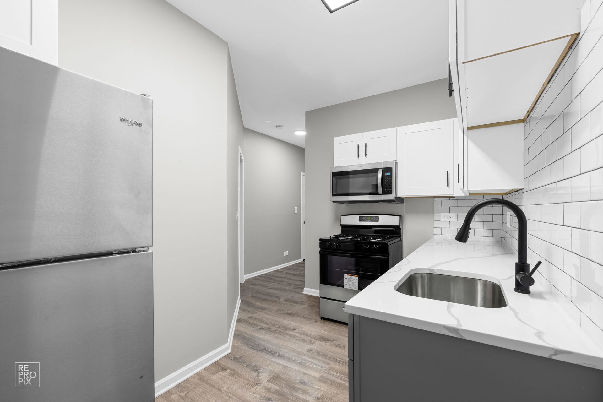Small kitchen with stainless steel appliances, white cabinets, and subway tile backsplash.