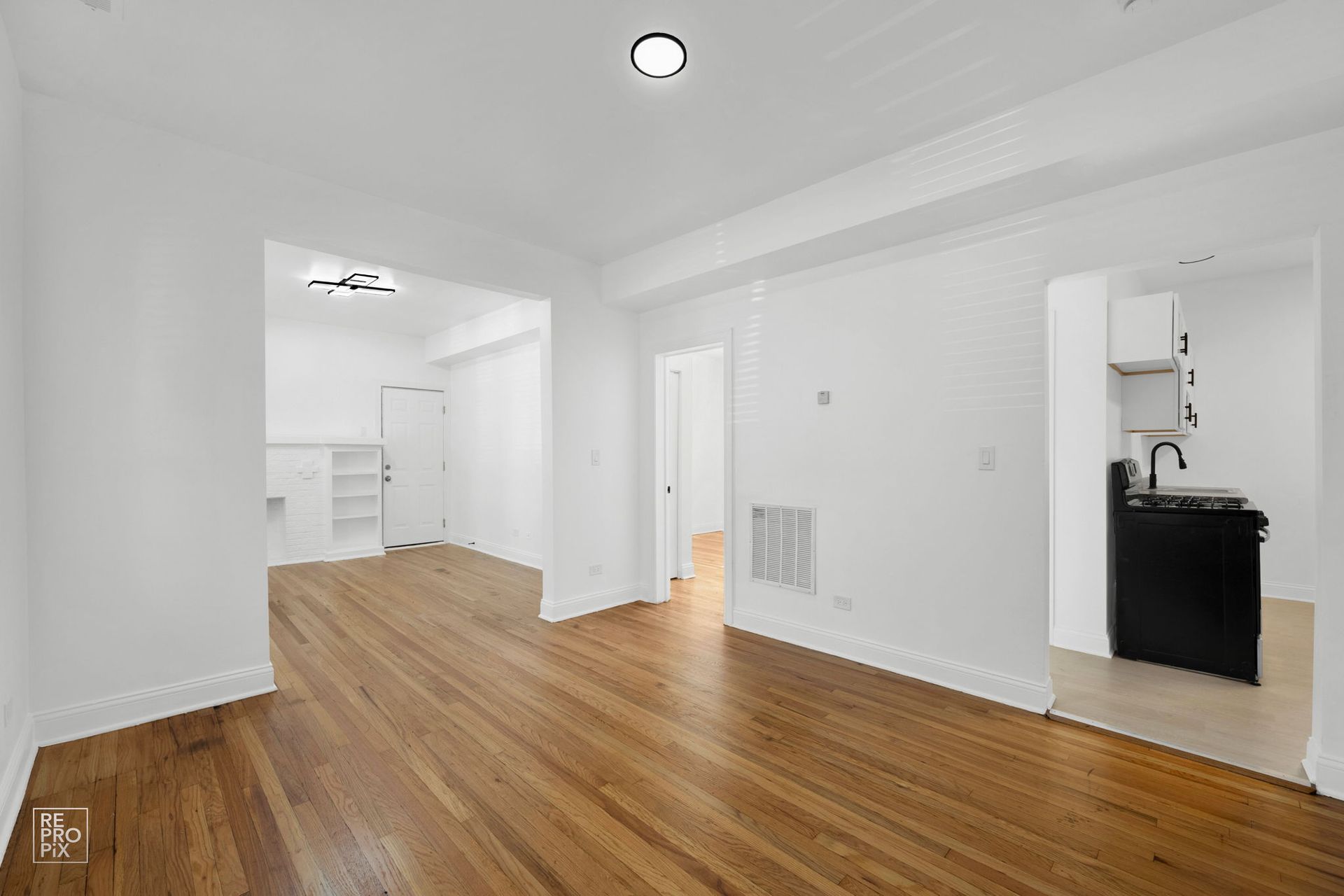 Empty apartment interior with hardwood floors and white walls.