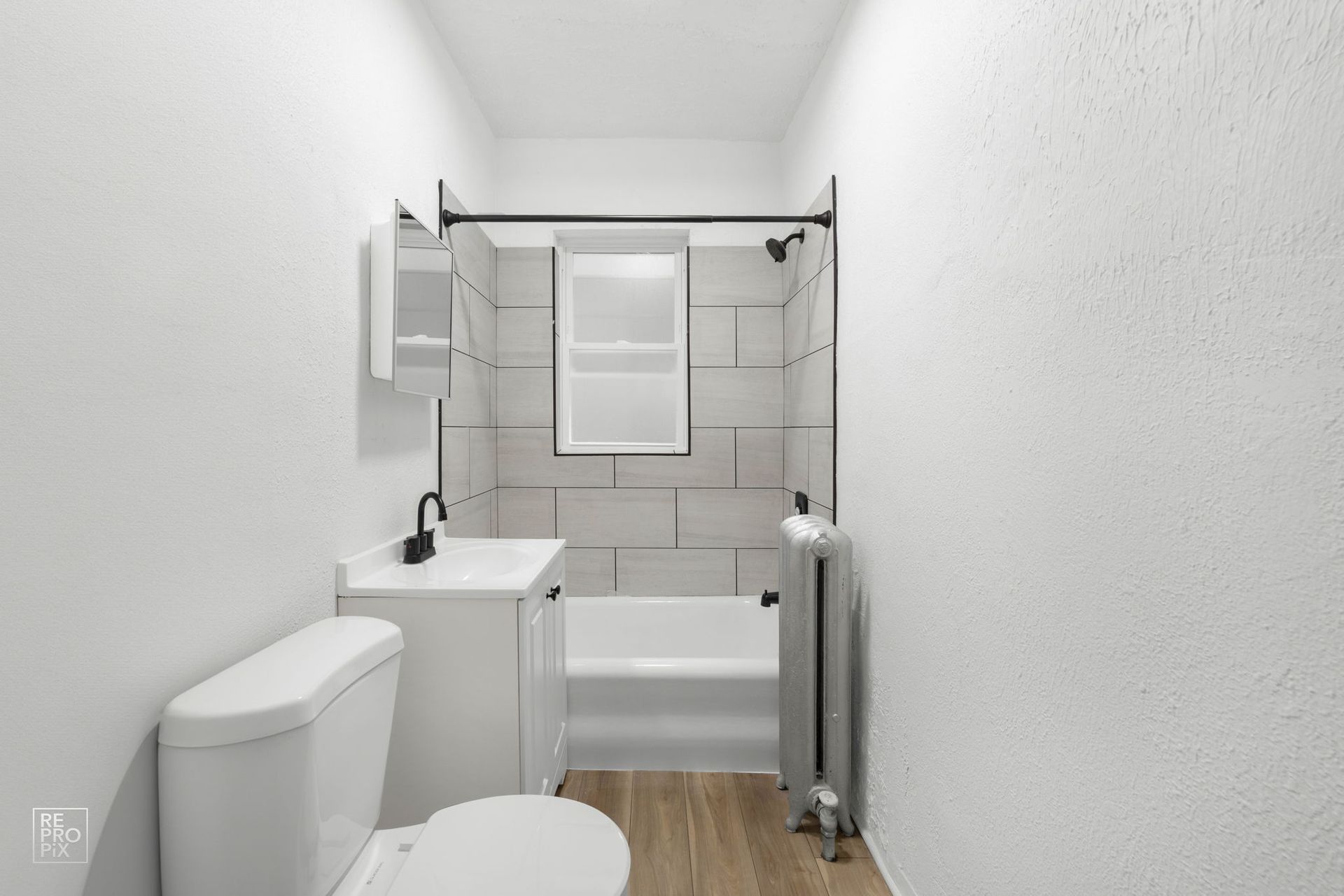 Small, white bathroom with toilet, sink, tub, and black fixtures.