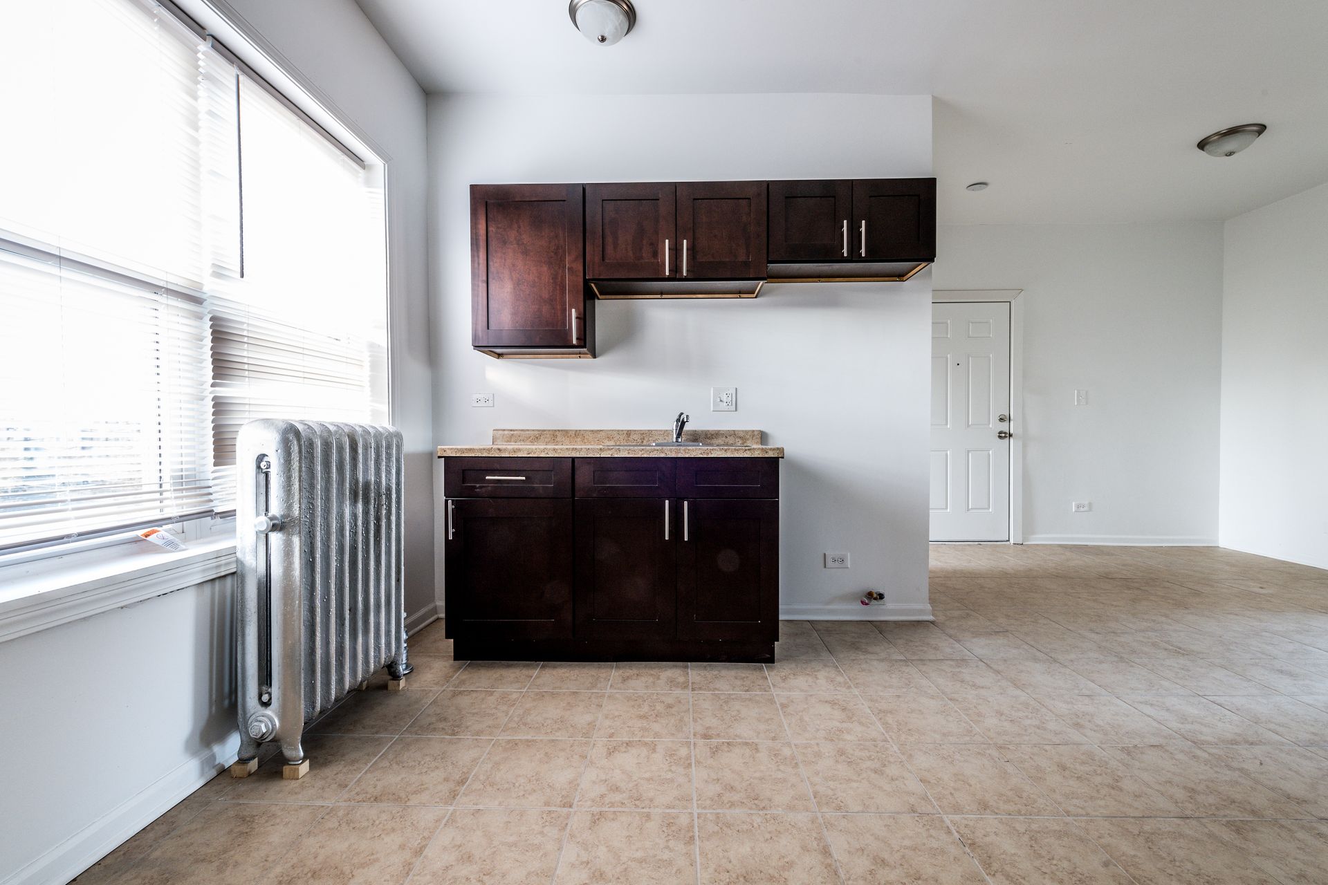 Small kitchen with dark cabinets, countertop, and a window with blinds.