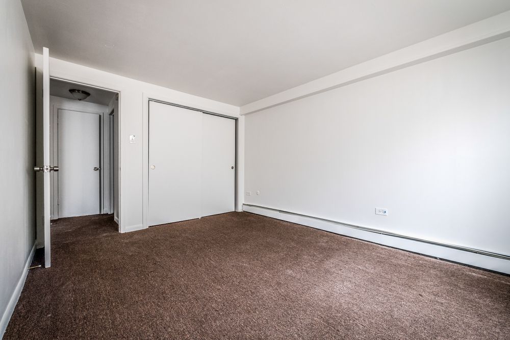 Empty room with brown carpet, white walls, closet, and a doorway.