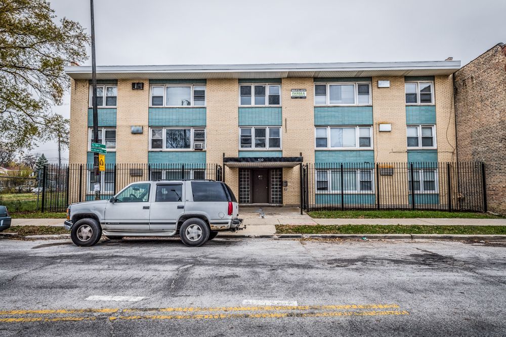 Two-story apartment building with teal accents; SUV parked out front.