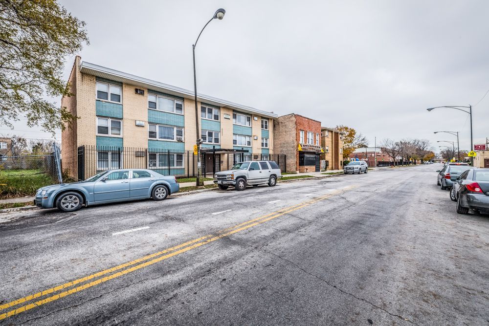 Apartment building and street on an overcast day. Cars are parked along the street.
