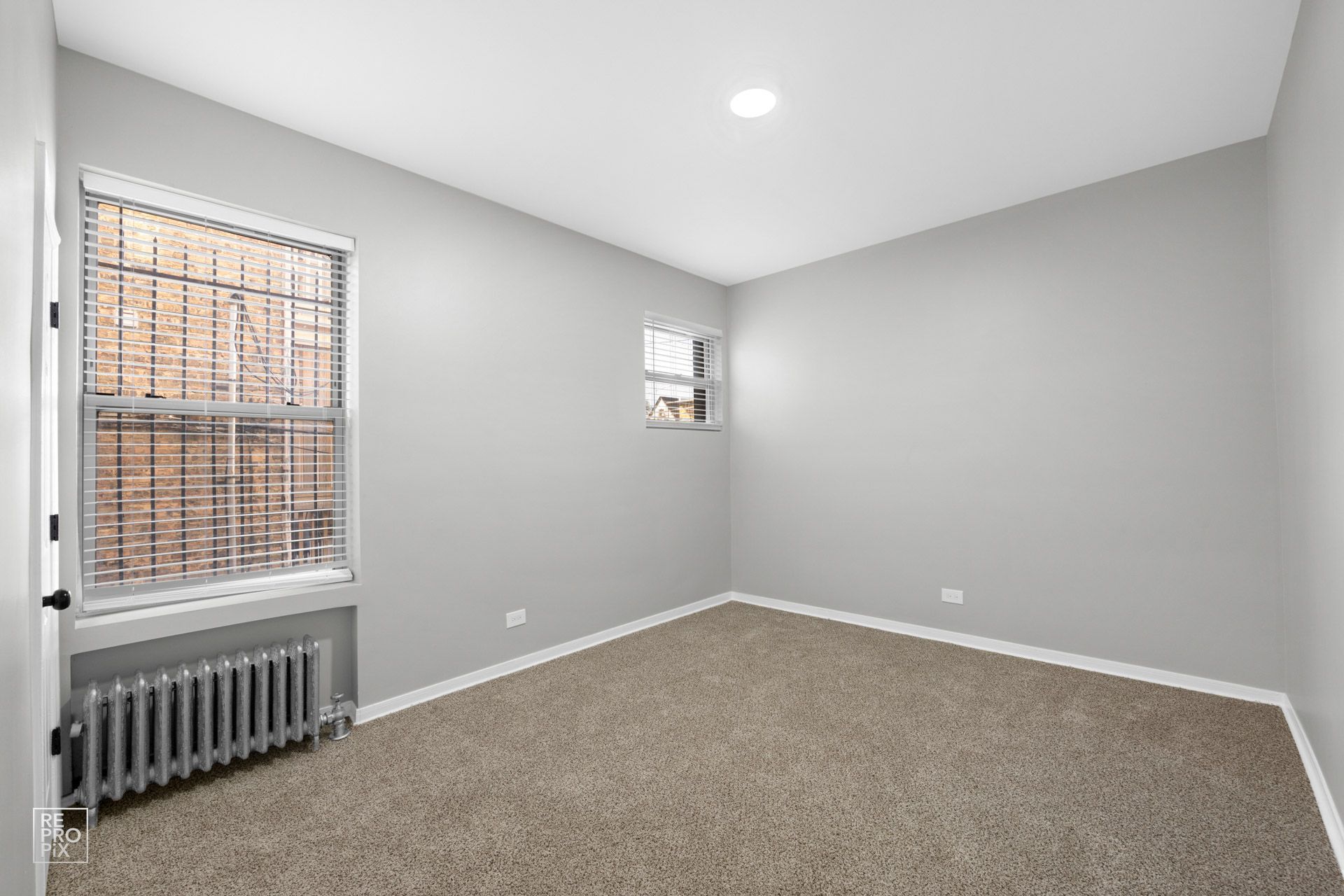 Bathroom with gray walls, white fixtures, wood-look floor, and a window.