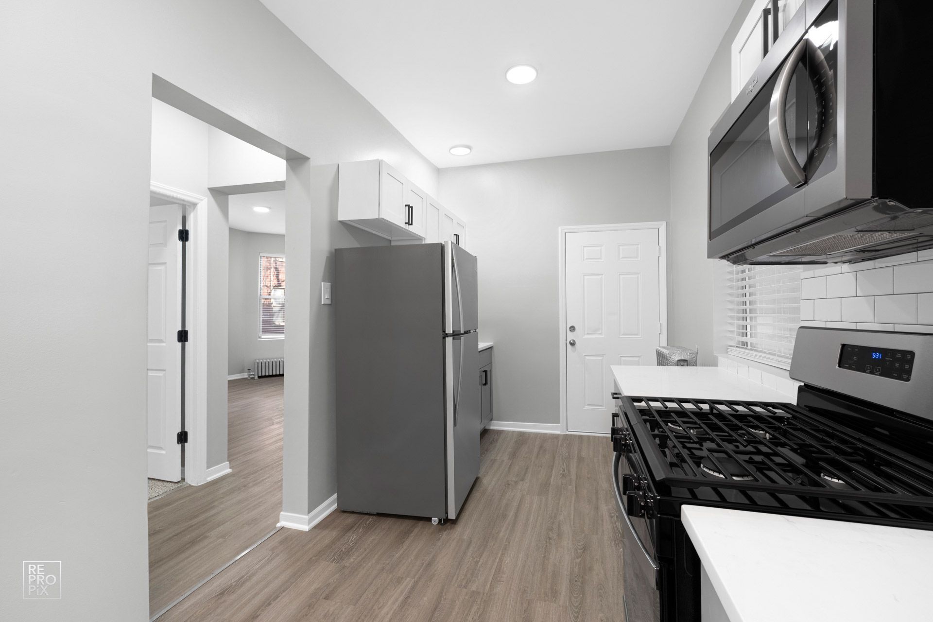 Kitchen with gray walls, stainless steel appliances, and wood-look flooring.