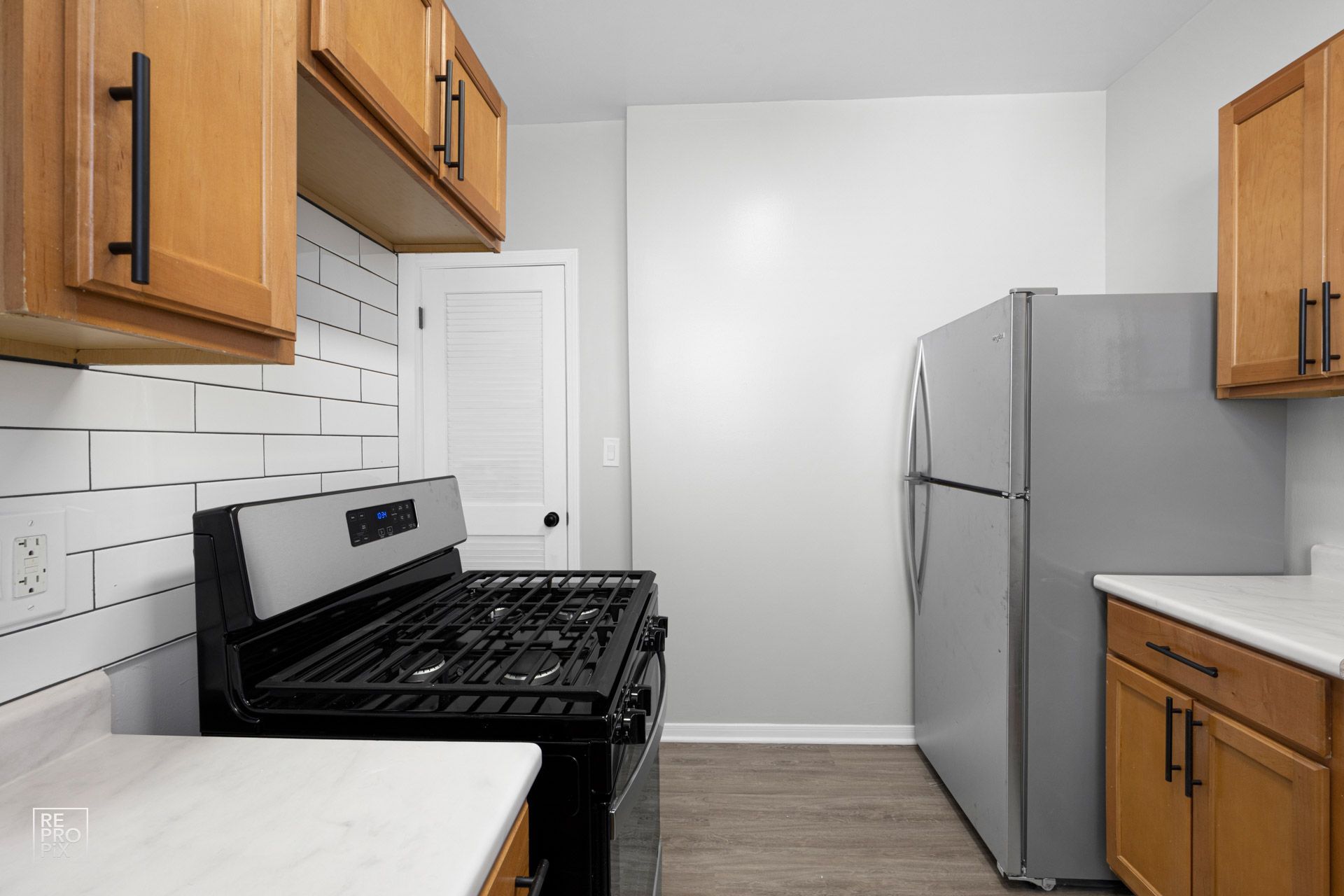 Kitchen with light wood cabinets, white countertops, stainless steel appliances, and subway tile backsplash.