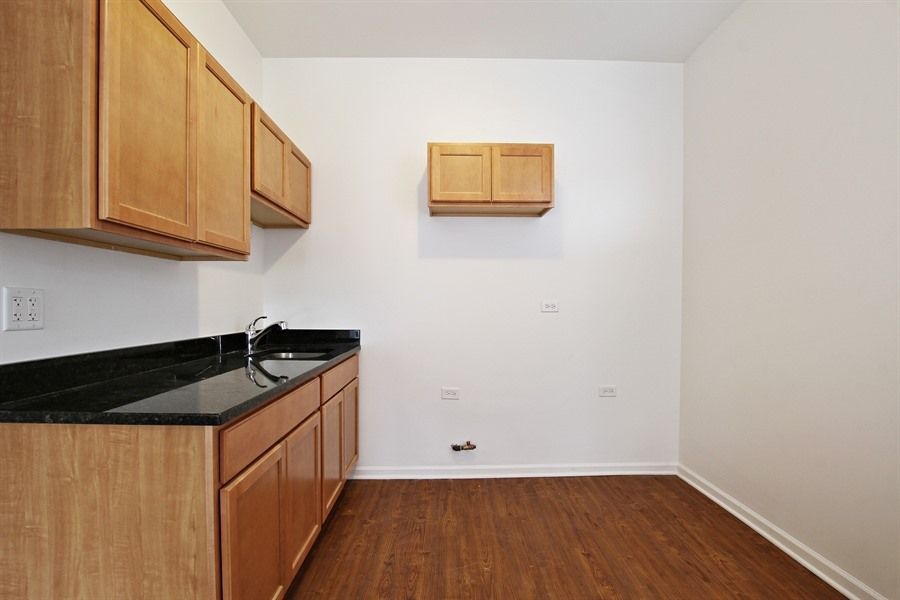 Kitchen with wooden cabinets, black countertop, sink, and wood-look flooring.