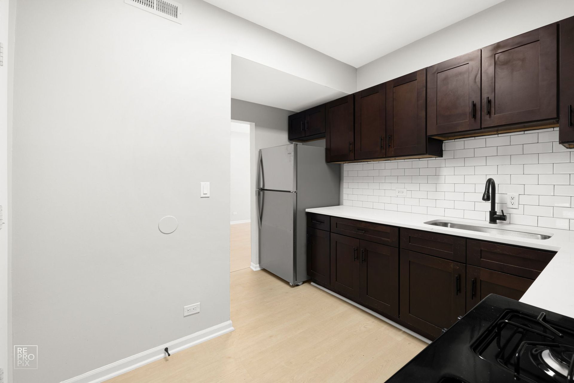 Kitchen with dark brown cabinets, white countertops, and subway tile backsplash.