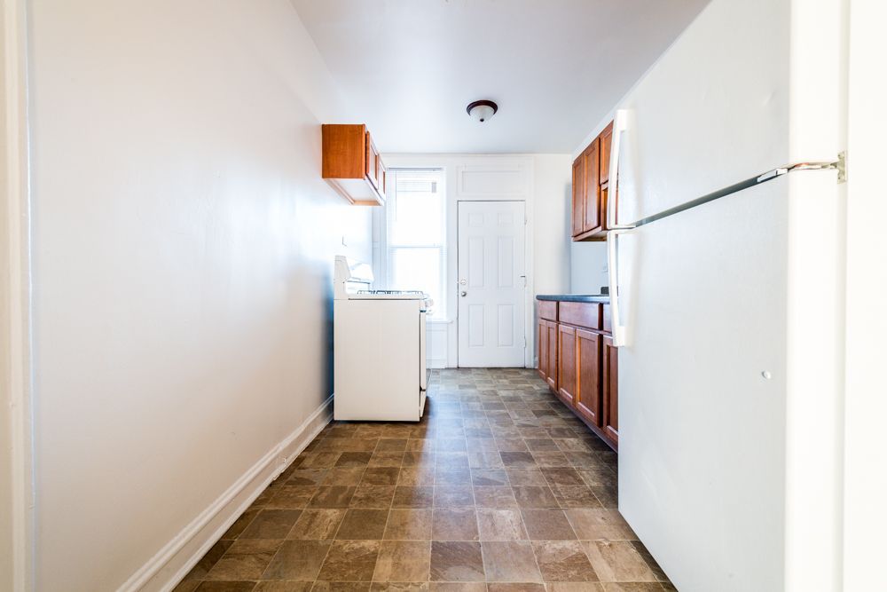 Small kitchen with white appliances, wooden cabinets, and linoleum flooring.