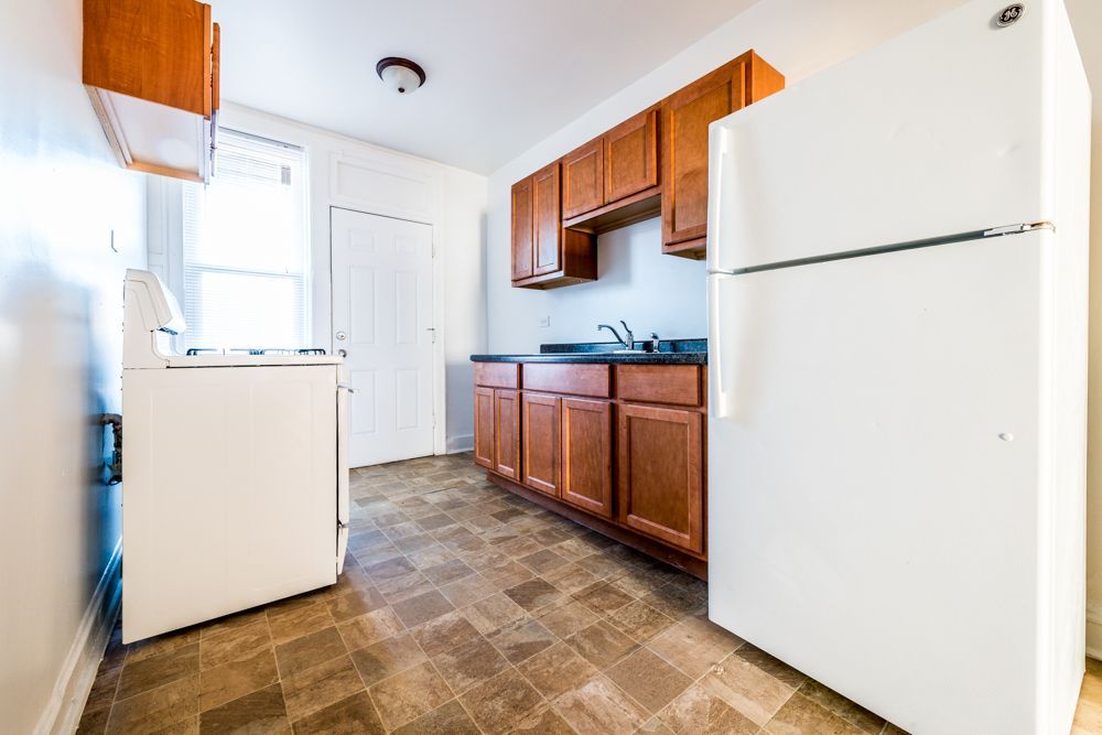 Kitchen with white appliances, brown cabinets, and patterned floor.
