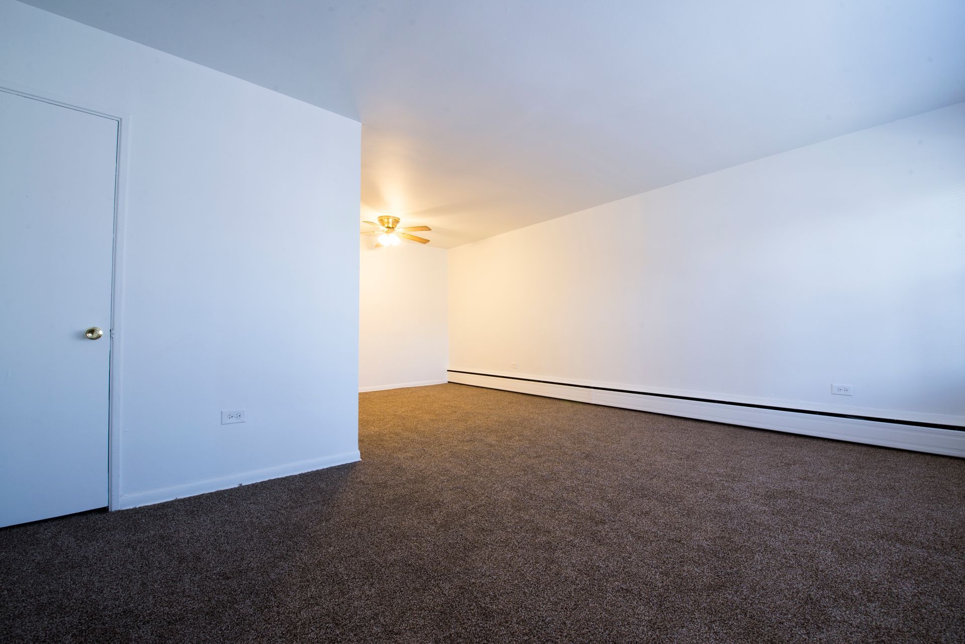 Empty room with brown carpet, white walls, and closed door.
