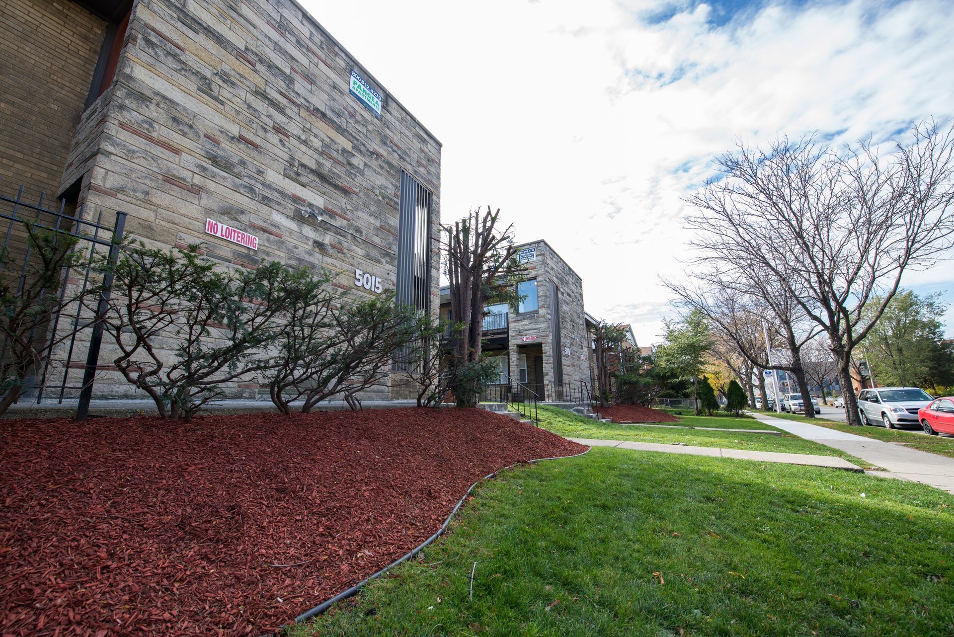 Brick building and residential homes with green grass and mulch. Sunny day.