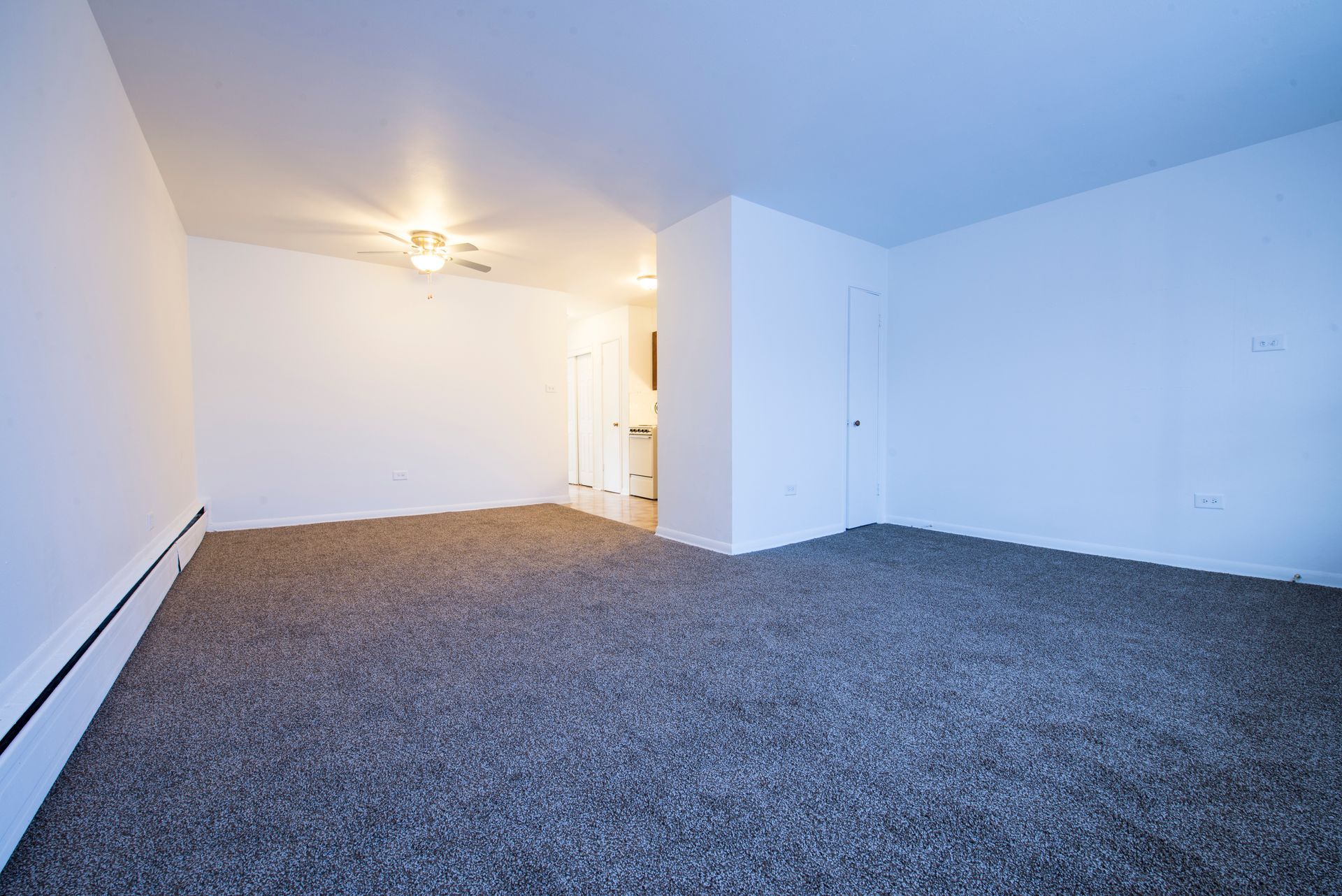 Empty room with gray carpet, white walls, and a doorway leading to another room.