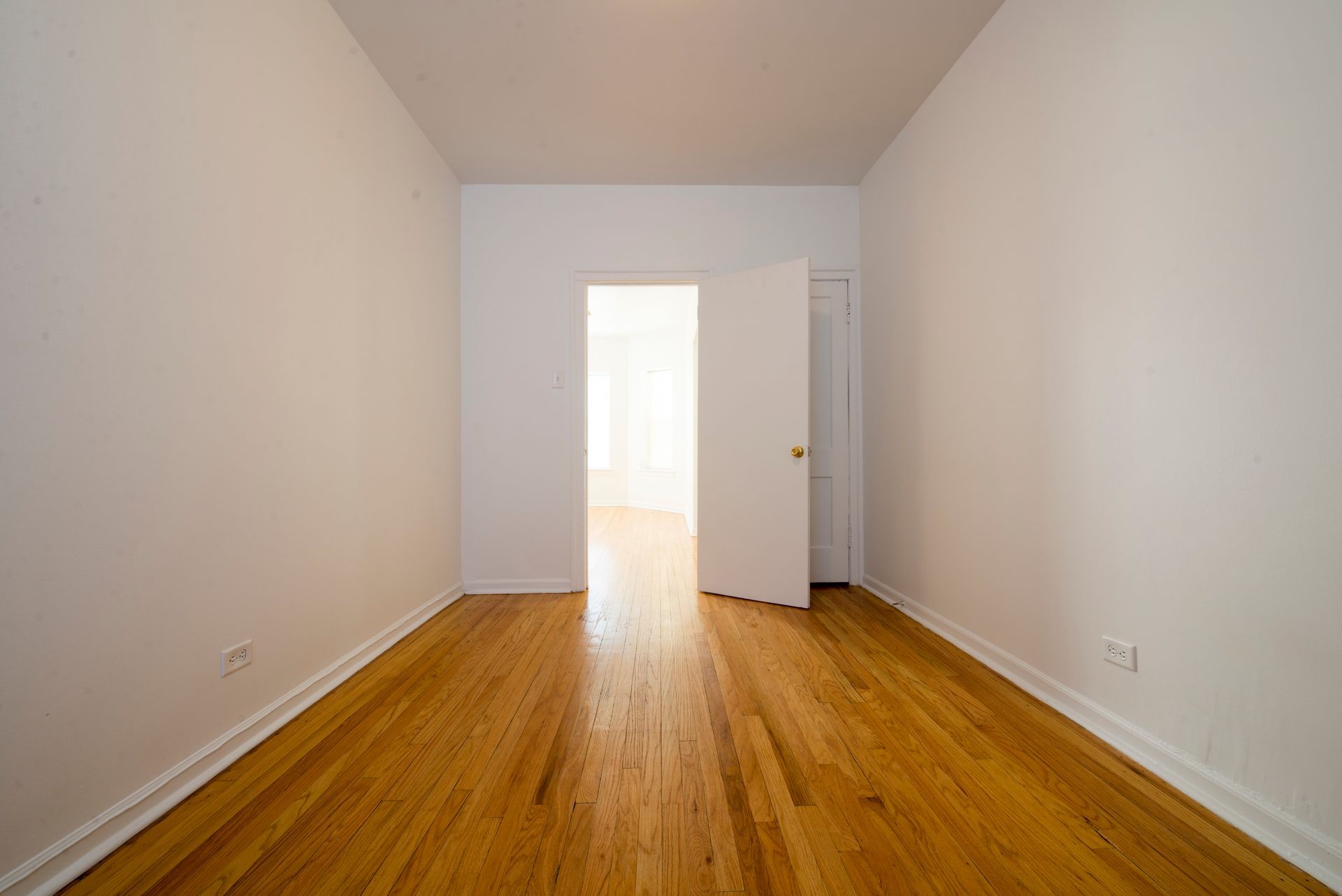 Empty room with hardwood floors and an open doorway.