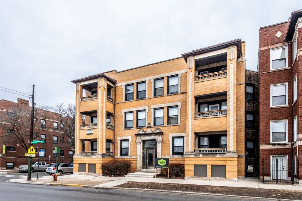 Multi-story apartment building with yellow and brick facade.