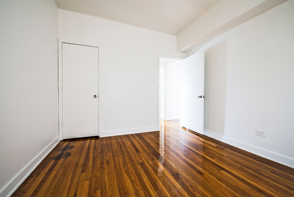 Empty room with hardwood floors, white walls, two white doors, one open.