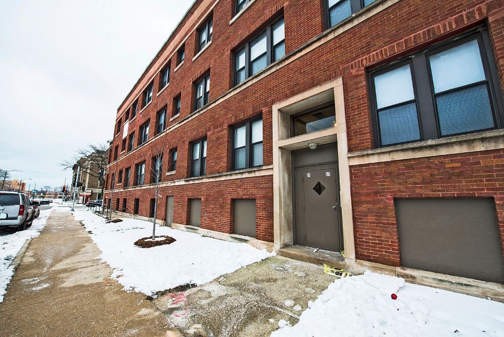 Brick apartment building entrance, snow on sidewalk.