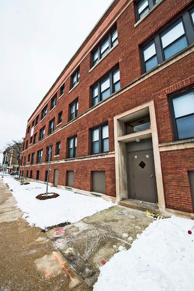 Red brick apartment building with snow on the ground and sidewalk.