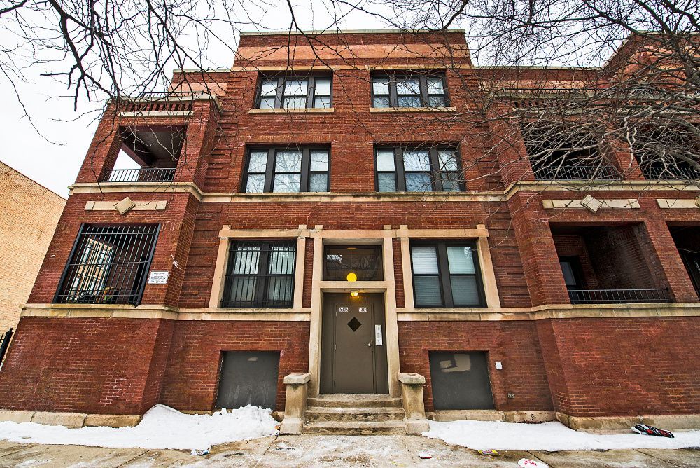 Red brick apartment building with dark trim, snow on ground.