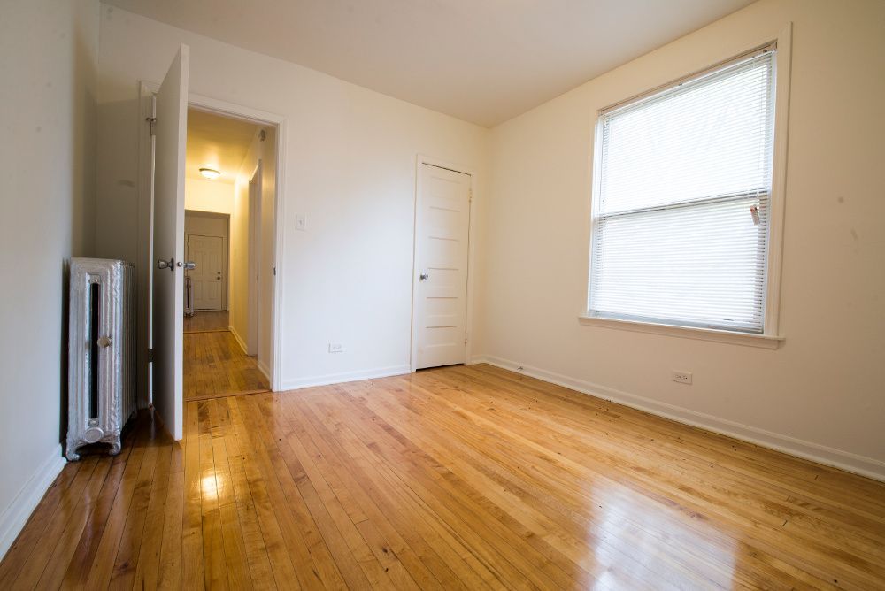 Empty room with hardwood floors, a closed door, window, and radiator.