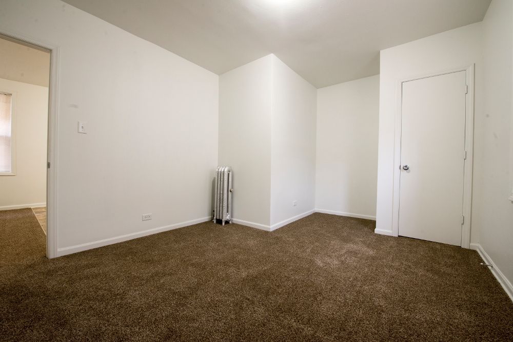 Empty room with brown carpet, white walls, and a closed white door.