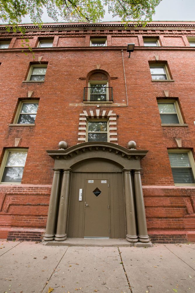 Red brick building with arched doorway and multiple windows.